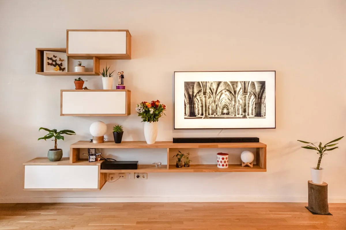 Tall modern wooden shelving unit reaching near the ceiling in a small apartment living room with books and plants