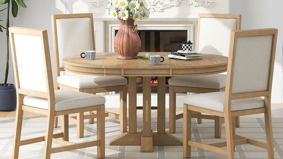 Classic round wooden pedestal dining table with four chairs centered in a bright room