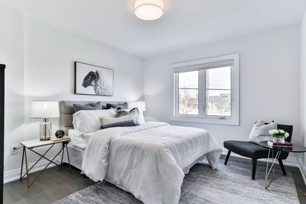 Modern bedroom featuring indirect warm white LED strip lighting behind a wooden headboard casting soft wall glow
