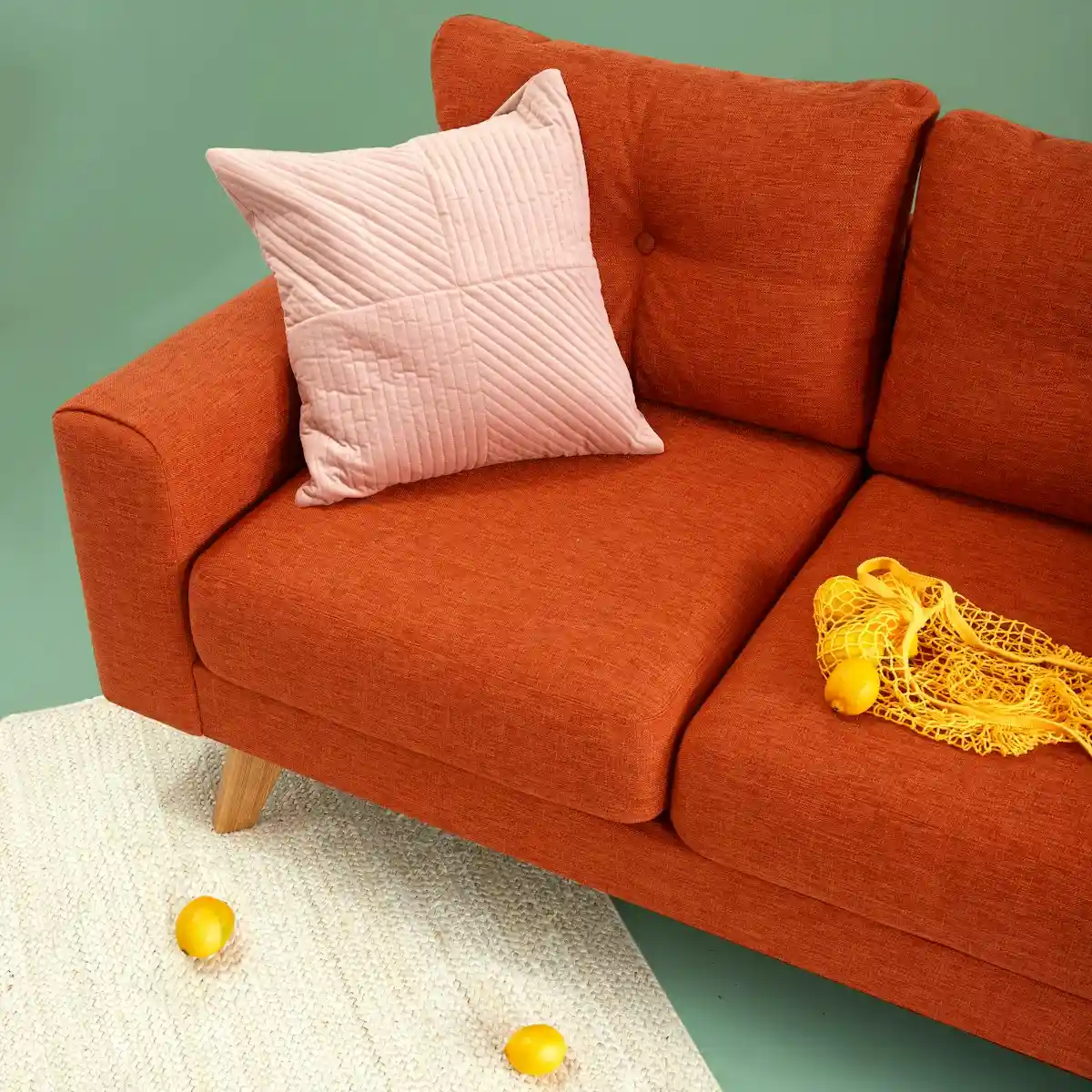 Detail of an inviting neutral sofa featuring textured boucle throw pillows and warm linen drapery in soft ambient light