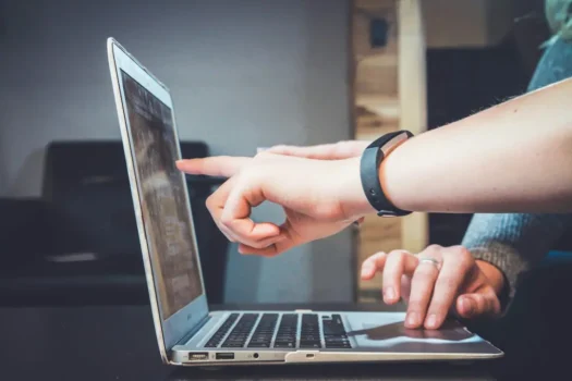 Telecom Expense Management Software - Employees discussing telecom expense management software on laptop and pointing at screen